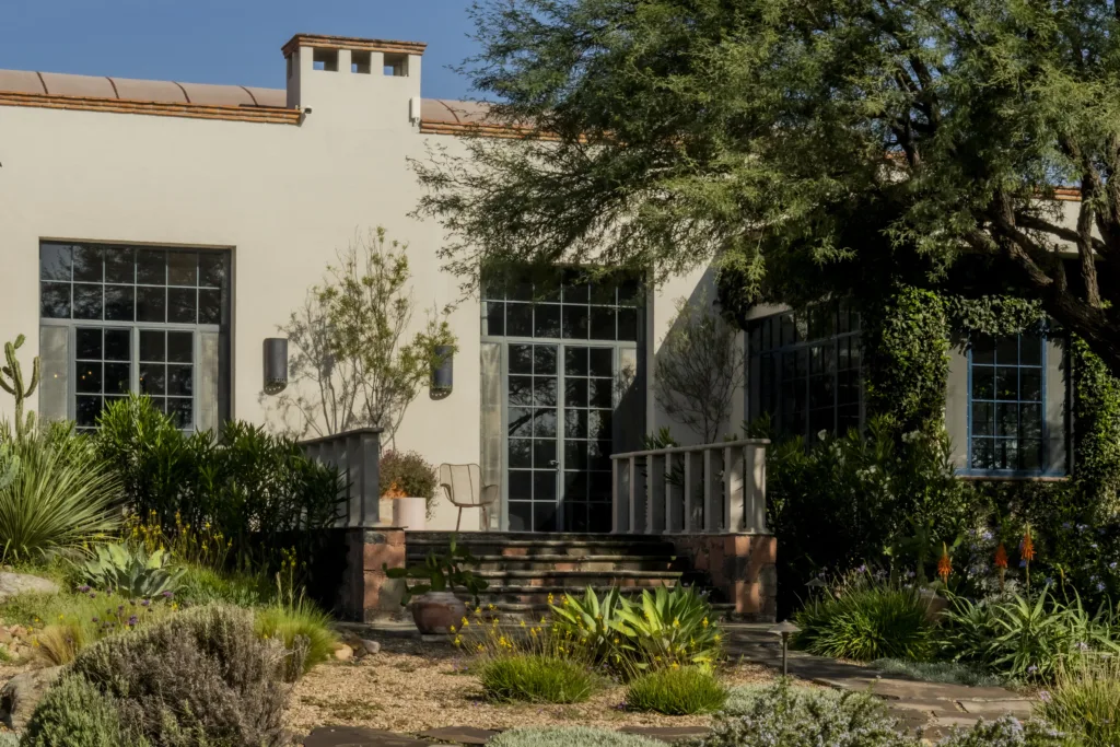 Hacienda Amor’s facade among agaves and mesquite trees, with a stone stairway and steel-framed windows, in San Miguel de Allende