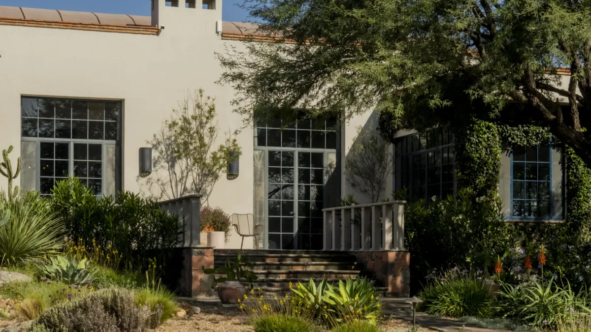 Hacienda Amor’s facade among agaves and mesquite trees, with a stone stairway and steel-framed windows, in San Miguel de Allende
